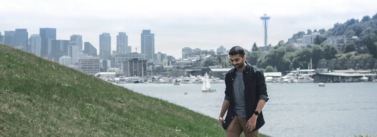 Person hiking alongside water with seattle skyline backdrop